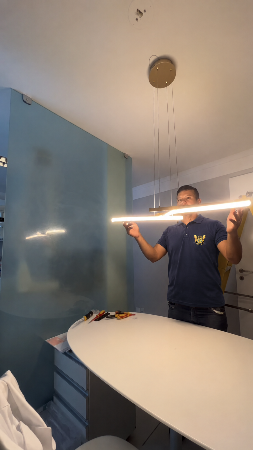 Instalação de luminária pendente de LED sobre mesa branca, com a camisa da RFC